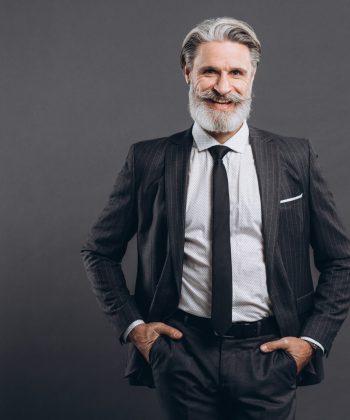 Portrait of a stylish and fashionable mature man in a gray suit. Business and trendy close-up concept on the grey background.